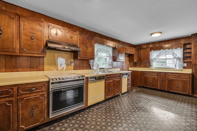253 Main St, Ducktown, TN 37326 - kitchen featuring dishwashing machine, under cabinet range hood, a textured ceiling, oven, and wooden walls