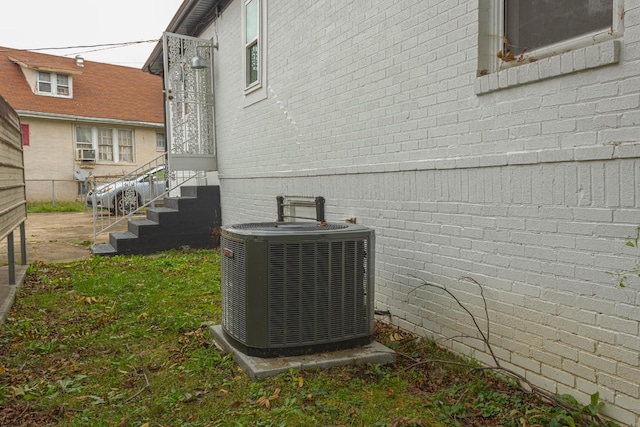 exterior details with fence, brick siding, central AC unit, and entry steps