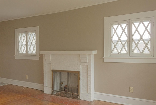 unfurnished living room with plenty of natural light, a fireplace, crown molding, and baseboards