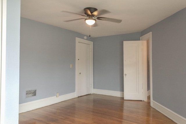 empty room featuring baseboards, wood finished floors, visible vents, and ceiling fan