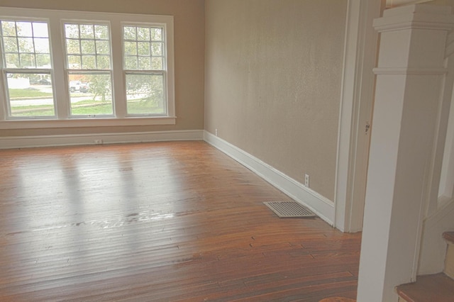 unfurnished room featuring visible vents, wood-type flooring, and baseboards