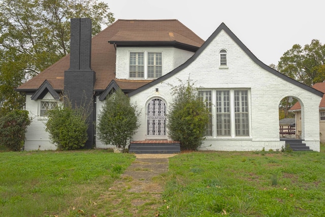 view of front of property with a front lawn, brick siding, and a chimney