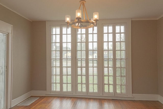 doorway featuring visible vents, baseboards, wood finished floors, and crown molding