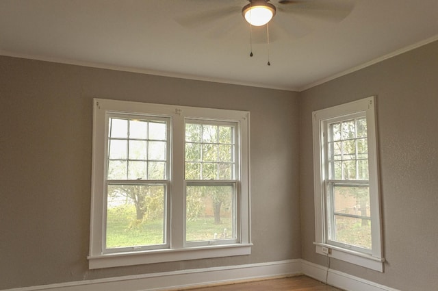 spare room with baseboards, ceiling fan, and crown molding