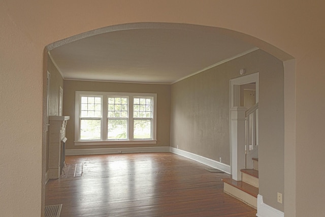 unfurnished room featuring visible vents, wood finished floors, ornamental molding, and stairs