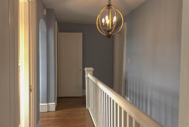 corridor featuring dark wood finished floors, an inviting chandelier, an upstairs landing, and baseboards