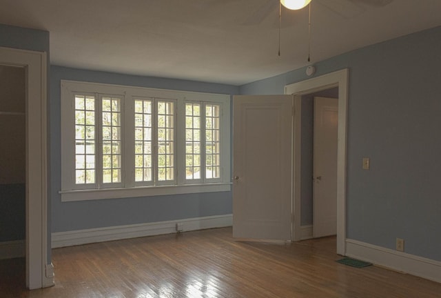 unfurnished room with ceiling fan, wood finished floors, visible vents, and baseboards