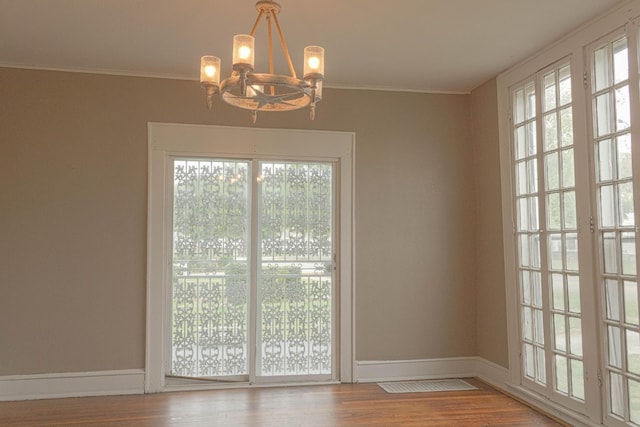 doorway to outside with plenty of natural light, crown molding, baseboards, and wood finished floors