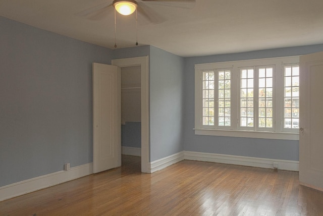 empty room with a ceiling fan, baseboards, and wood finished floors