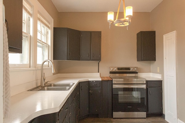 kitchen featuring a sink, stainless steel range with electric stovetop, pendant lighting, and light countertops