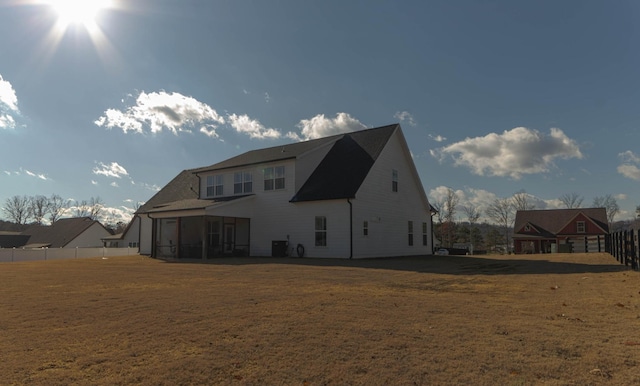 back of property featuring a yard, fence, and a sunroom