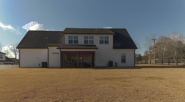 back of house featuring a lawn, a sunroom, central AC, and fence