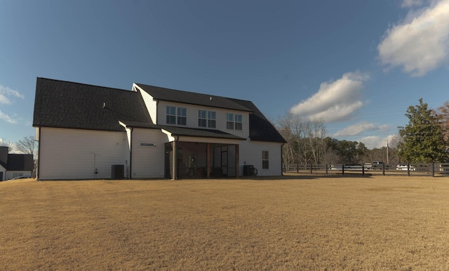 rear view of property with a yard, central AC, and a sunroom