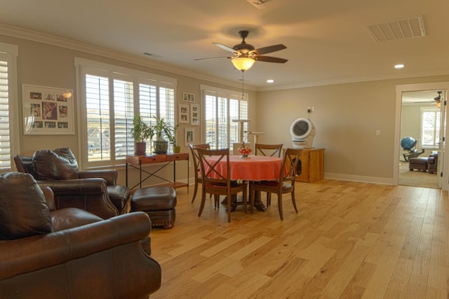 dining space featuring visible vents, plenty of natural light, light wood-style floors, and ornamental molding