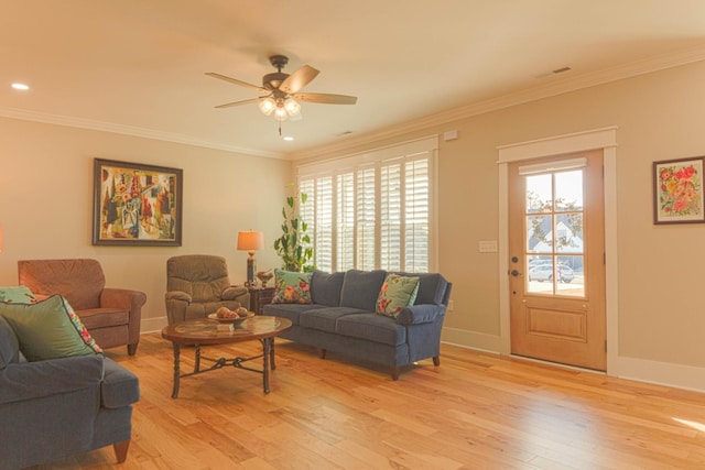 living area with crown molding, a healthy amount of sunlight, and light wood finished floors