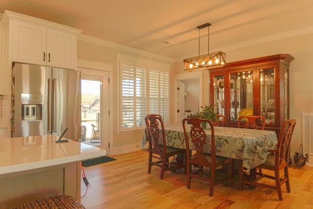 dining room with visible vents, a notable chandelier, crown molding, light wood finished floors, and baseboards