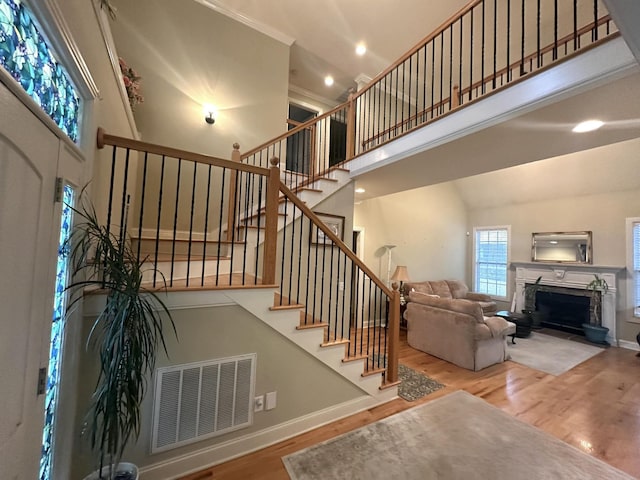 living room with visible vents, wood finished floors, a fireplace, baseboards, and a towering ceiling