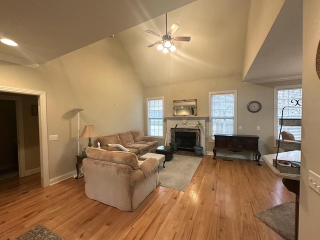 living area featuring high vaulted ceiling, a ceiling fan, wood finished floors, a fireplace, and baseboards