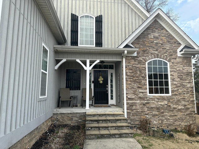 view of exterior entry with a porch, board and batten siding, and stone siding