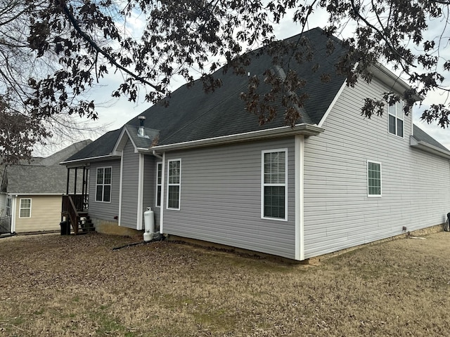 back of property with entry steps, a yard, and roof with shingles