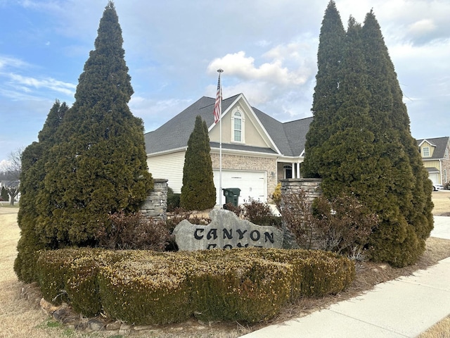 view of side of home featuring a garage, stone siding, and roof with shingles