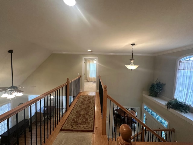 corridor with crown molding, an upstairs landing, and light wood-style floors