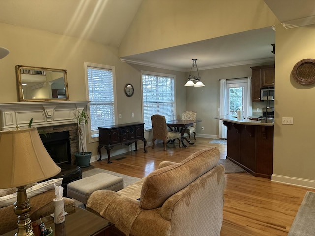 living room featuring baseboards, a stone fireplace, ornamental molding, and light wood finished floors