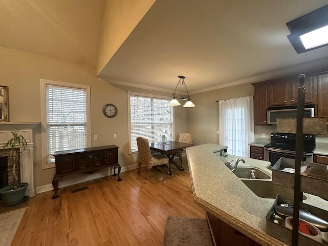 kitchen with electric range, a fireplace, crown molding, stainless steel microwave, and light wood-type flooring