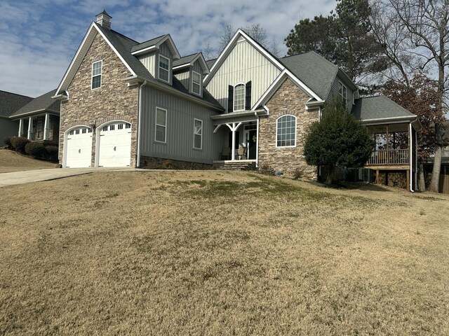 view of front of house with a chimney, stone siding, a front lawn, and a garage