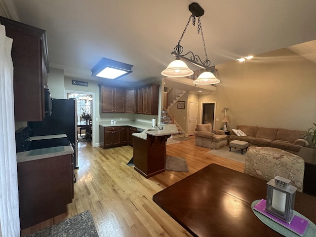 kitchen featuring open floor plan, light wood-style floors, a peninsula, light countertops, and dark brown cabinets