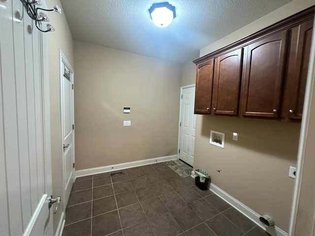 laundry room featuring baseboards, washer hookup, cabinet space, a textured ceiling, and dark tile patterned flooring