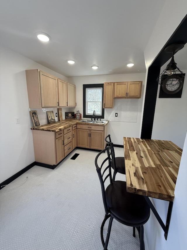 kitchen featuring light carpet, recessed lighting, baseboards, and a sink