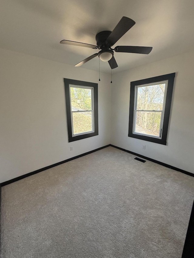 carpeted empty room featuring visible vents, ceiling fan, and baseboards