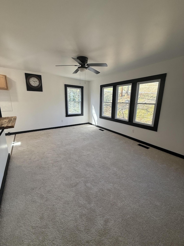 unfurnished room with visible vents, ceiling fan, baseboards, and carpet