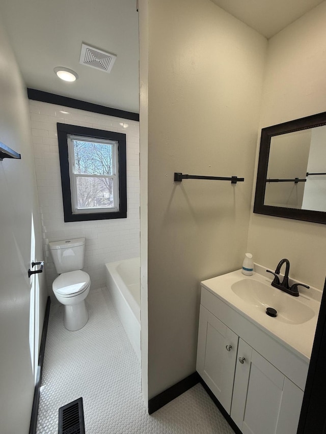 bathroom featuring vanity, toilet, a tub, and visible vents