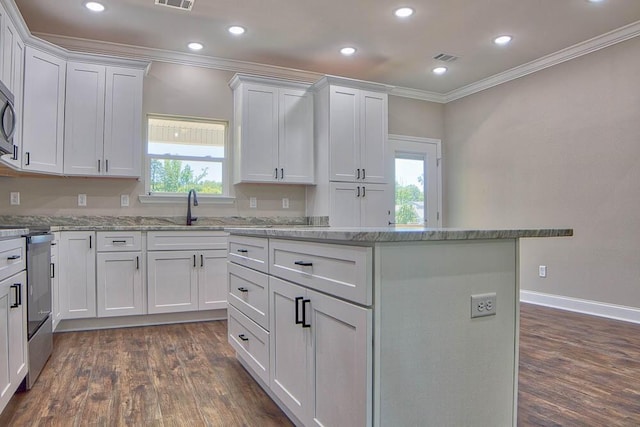 kitchen with a kitchen island, crown molding, range with electric stovetop, white cabinets, and a sink