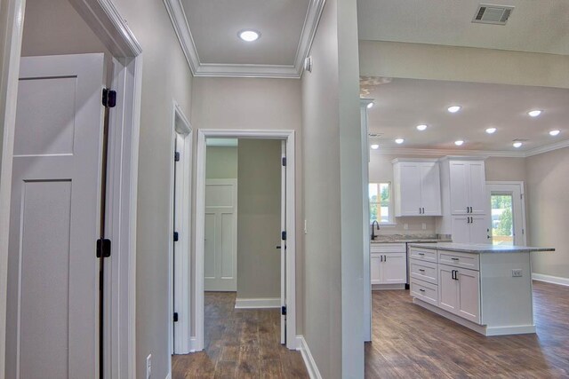 corridor with visible vents, baseboards, ornamental molding, and dark wood-style flooring