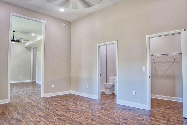 unfurnished bedroom with a spacious closet, ceiling fan, baseboards, wood finished floors, and ensuite bath