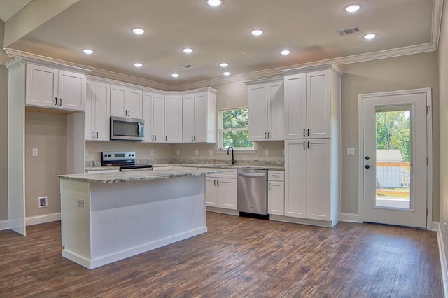 kitchen featuring visible vents, ornamental molding, appliances with stainless steel finishes, white cabinetry, and dark wood-style flooring