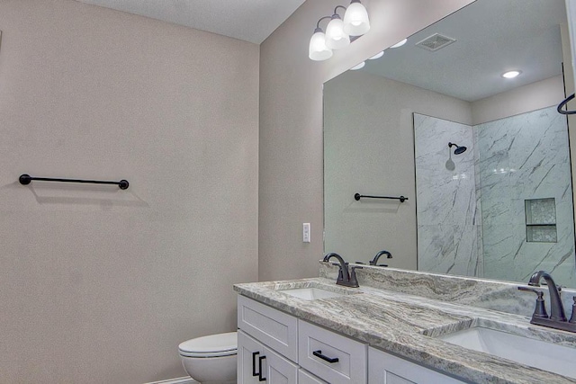 bathroom featuring toilet, visible vents, a marble finish shower, and a sink