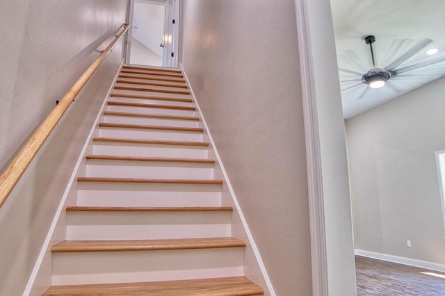 stairway with wood finished floors, baseboards, and a textured wall