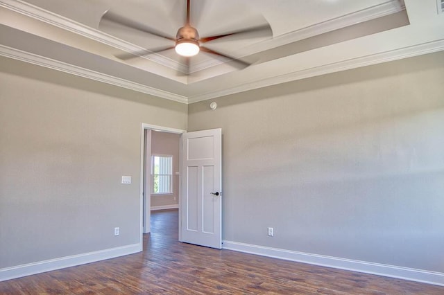 unfurnished room with dark wood finished floors, a ceiling fan, a tray ceiling, and ornamental molding