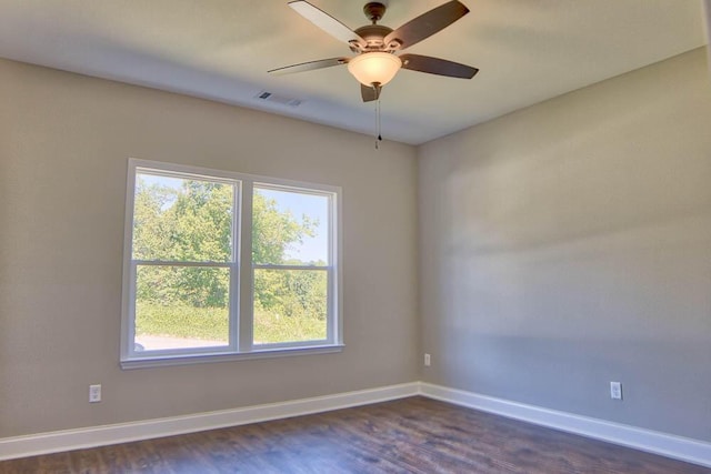 unfurnished room featuring visible vents, baseboards, dark wood-style floors, and a ceiling fan