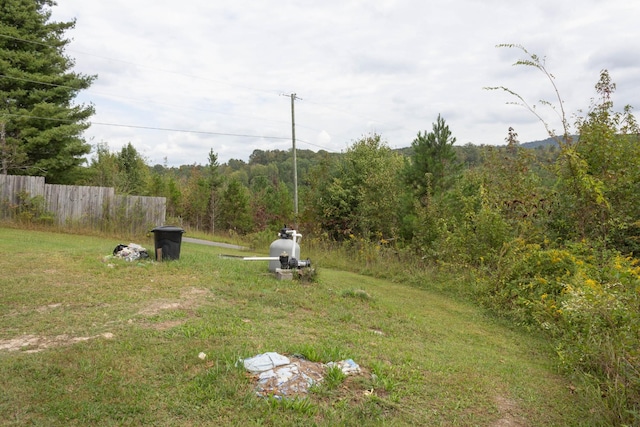 view of yard with a wooded view and fence