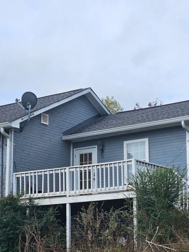 rear view of house featuring roof with shingles