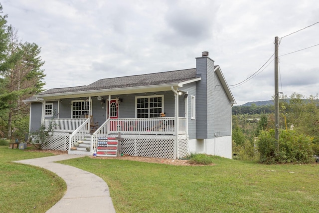 view of front of house with covered porch, a chimney, and a front lawn