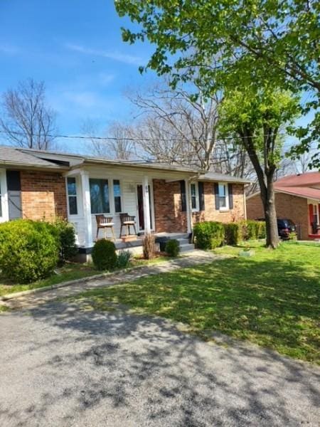 single story home with brick siding, covered porch, and a front yard