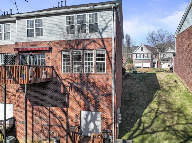 rear view of property featuring a yard, cooling unit, and brick siding