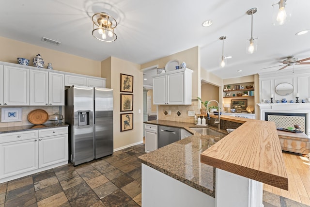 kitchen with visible vents, a sink, stone tile flooring, white cabinetry, and stainless steel appliances