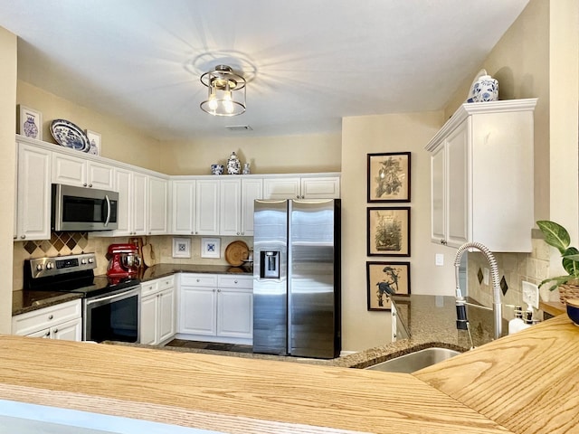 kitchen with visible vents, a sink, decorative backsplash, stainless steel appliances, and white cabinets